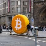 Een groot bitcoin logo in een drukke stad