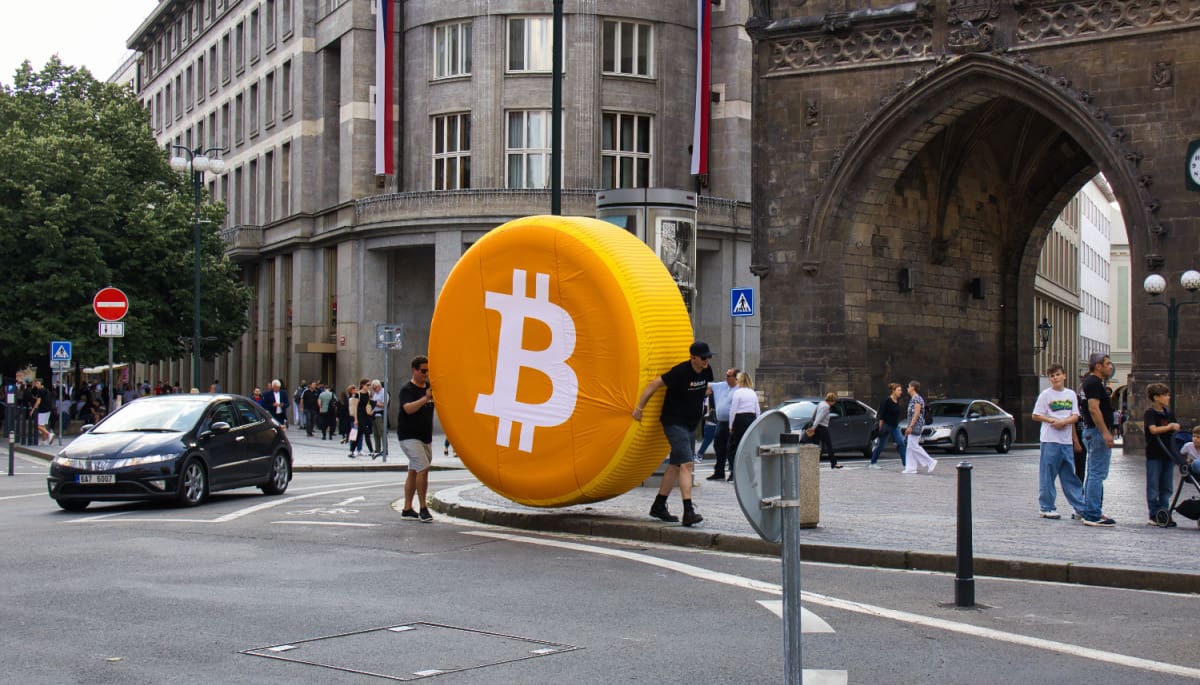 Een groot bitcoin logo in een drukke stad